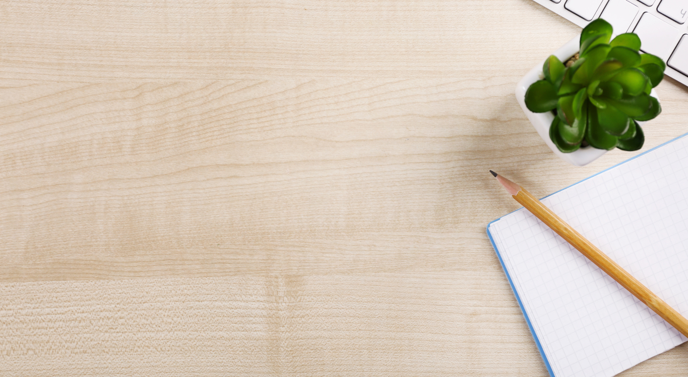 desk with laptop, plant, notepad, and pen